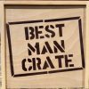 A wooden crate featuring bold, black stenciled lettering that reads "BEST MAN CRATE" on the front. The crate, perfect for holding the 4 Best Man items it comes with, has a natural wood grain and is set against a neutral background. Pair it with the included blue distressed hat for a complete gift ensemble.