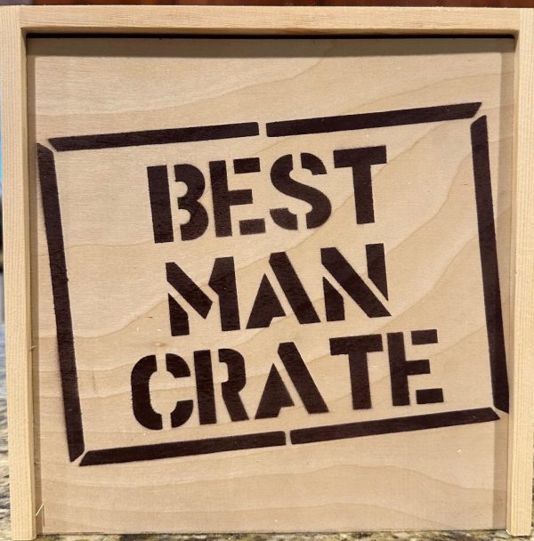 A wooden crate featuring bold, black stenciled lettering that reads "BEST MAN CRATE" on the front. The crate, perfect for holding the 4 Best Man items it comes with, has a natural wood grain and is set against a neutral background. Pair it with the included blue distressed hat for a complete gift ensemble.