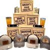 A display of wooden crates labeled for various wedding roles, such as "Groom's Man," "Ring Bearer," and "Father in Law." One crate is the Best Man Crate with 4 Best Man Items, including a blue distressed hat. In front of the crates are caps and drinkware with matching labels. Additionally, there is a bottle opener, flasks, and a pint glass included.