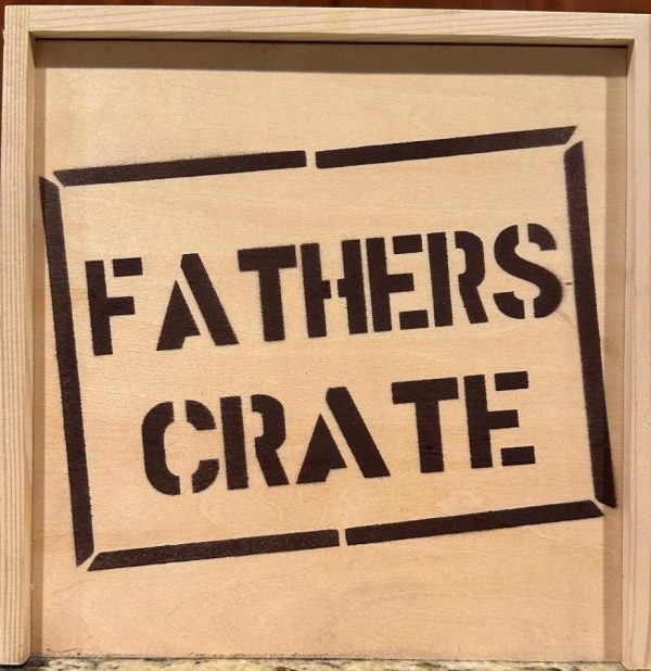 The Fathers Crate - Wooden Gift Box features the words "FATHERS CRATE" prominently stenciled in bold black letters on the front, enclosed within a rectangular border. The crate is crafted from light-colored wood and boasts a simple, rustic design, making it an ideal gift for Dad.