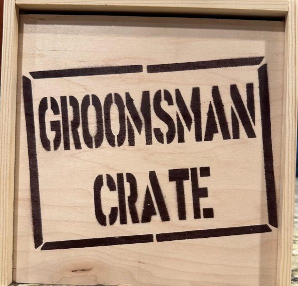 The "Groomsman Crate - Wooden Gift Box" features the words "GROOMSMAN CRATE" boldly stenciled in uppercase letters on the front, framed by a rectangular border, and boasts a light, natural wood grain finish.