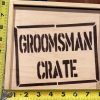 The Groomsman Crate - Wooden Gift Box features "GROOMSMAN CRATE" stenciled in black letters on its lid. Measured with a yellow tape measure, it shows approximately 10 inches in width and 7.5 inches in height, making it the perfect size for any groomsman's essentials.